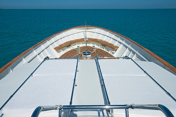 View over the bow over a large motor yacht with sun beds