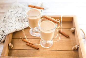 Traditional winter eggnog in glass mug with milk, rum and cinnamon, christmas decorations.
