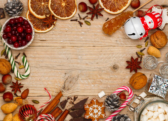 Culinary Christmas background of nuts (hazelnuts, walnuts, almonds), spices (cinnamon, star anise, cloves, cardamom), chocolate, caramel, cranberries, Christmas toys and garlands. Top view, Copy space