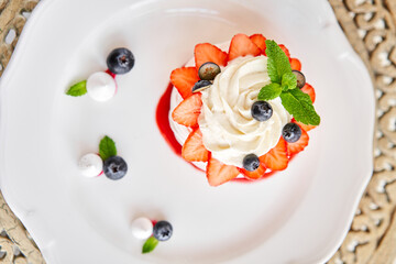 Pavlova is a meringue-based dessert with a crisp crust topped. Decorated strawberry, mint leaf, blueberry and whipped cream. Restaurant sweet food