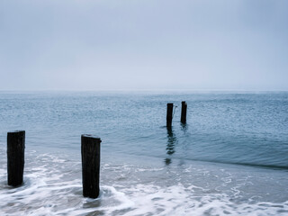 Seascape with four pilings of ruined piers