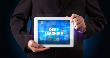 Young business person working on tablet and shows the inscription: DEEP LEARNING