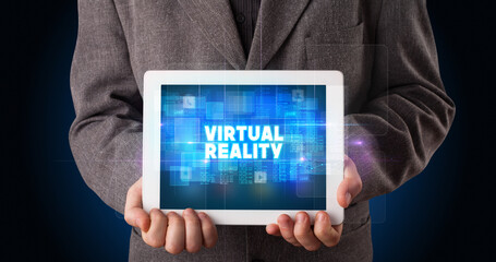 Young business person working on tablet and shows the inscription: VIRTUAL REALITY