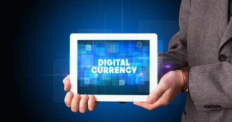 Young business person working on tablet and shows the inscription: DIGITAL CURRENCY