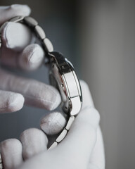 Hands in white gloves show the polish on the stainless steel watch case