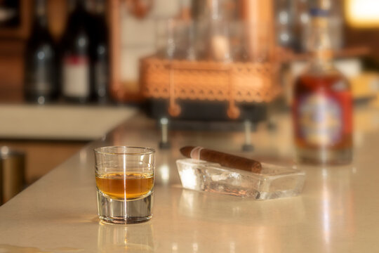Whiskey glass and cigar standing on the bar table.