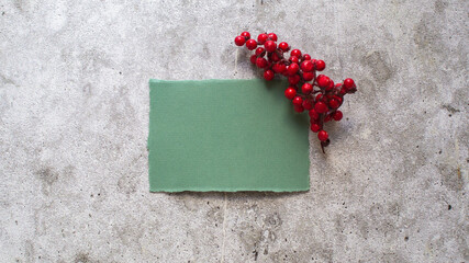 green blank card with red berries branch on concrete background. Holiday mock up. Christmas mock up.