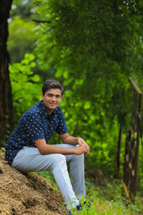 Naklejka na ściany i meble Young indian man in blue shirt over nature background