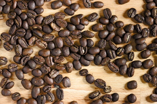 Top down view of spread coffee beans on wooden table. Concept of coffee culture. © Ivana
