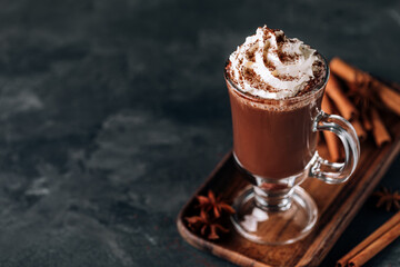 Hot chocolate cocoa with whipped cream in glass on dark background, copy space.
