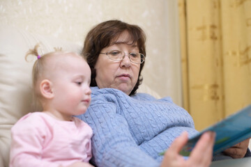 grandmother shows granddaughter a children's book, selective focus on woman