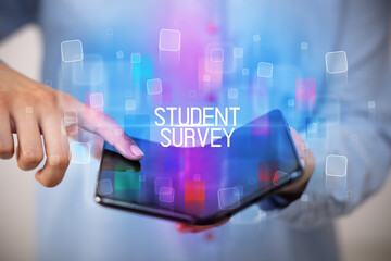 Young man holding a foldable smartphone with STUDENT SURVEY inscription, educational concept