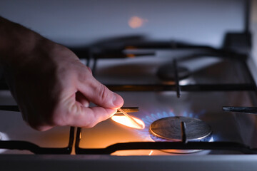 A man lights a gas stove with a match