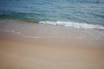 젖은 모래와 잔잔한 파도가 치는 바다의 풍경