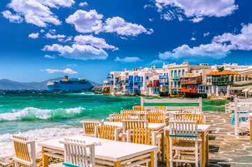Little Venice, Mykonos island, Greece. Colorful buildings and balconies near the sea and a large white cruise ship.