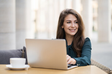 prints writes the text of the message a report on the work on marketing investing in a new company. young female student Manager Caucasian appearance brunette sitting in a summer cafe drinking coffee.