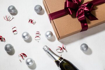 Obraz na płótnie Canvas Christmas celebration flat lay. New Year composition. Bottle of Champagne, decorations, confetti, gift box in silver and red colors. New Year's eve. Christmas concept