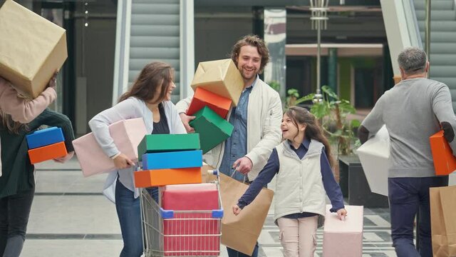 Family Spending Weekend in The Shopping Mall. Smiled Parents Walking Hand in Hand With a Daughter With Bags From Shop. Family Christmas Shopping.