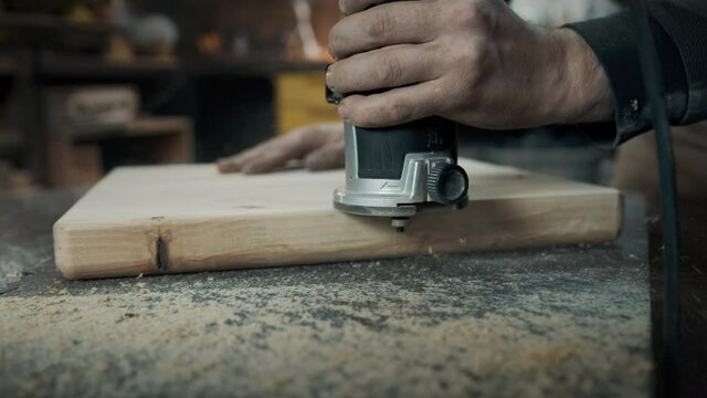 A carpenter mills the edges of a wood loft chair.
