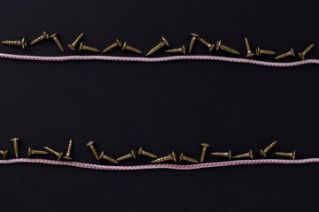 the background for the text is made of self-tapping screws and rope on a black background (top view).
