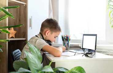 Distance learning online education. A schoolboy is studying at a computer at home and doing school homework. quarantine coronavirus.