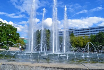 Fototapeta premium Fountain and blue sky during sunny day. A working fountain near the red tower in the city center of the Chemnitz, East Germany.