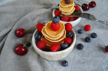 Pancake cereal, mini pancakes in a bowl with blueberries, raspberries, cherries. Healthy nutrition. Culinary trend. Homemade food.