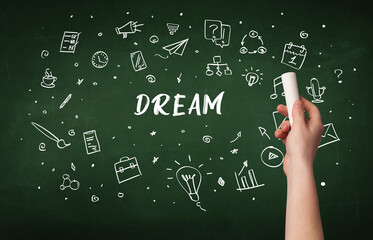 Hand drawing DREAM inscription with white chalk on blackboard, education concept