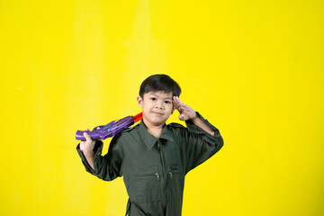 Asian boy in military uniform holding a gun, Fun gestures, Copy space.
