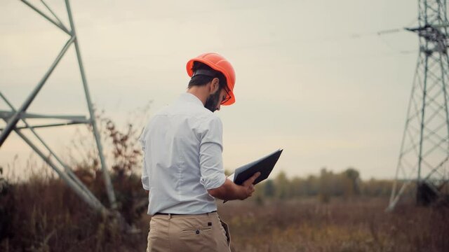 Electrical Engineer In Helmet On Power Lines.Technician Inspect High Voltage Tower.Engineer In Hardhat Maintenance Electricity Transmission Pylon.Technician Check High Voltage Sensor Power Line Wires.