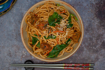 Korean kimchi and seitan fried noodles in bowl with chopsticks, copy space
