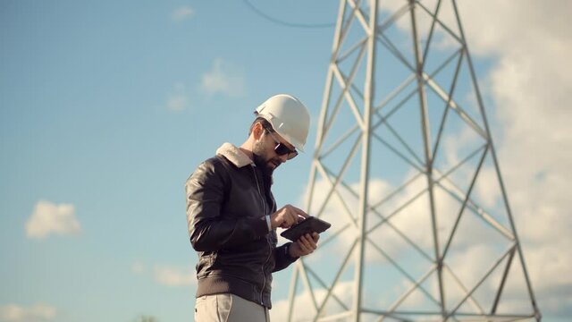 Electrical Engineer In Helmet On Power Lines.Technician Inspect High Voltage Tower.Engineer In Hardhat Maintenance Electricity Transmission Pylon.Technician Check High Voltage Sensor Power Line Wires.