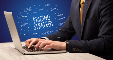 Businessman working on laptop with PRICING STRATEGY inscription, online shopping concept