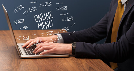 Businessman working on laptop with ONLINE MENU inscription, online shopping concept