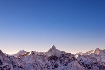 Himalayan mountain range with majestic morning light. Ama Dablam peak on Everest base camp trek. Blue sky and beautiful mountains background.