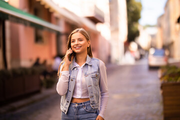 Fototapeta premium Young pretty woman talking on mobile phone on the street