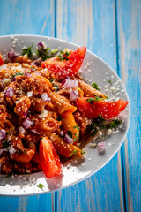 Penne with pork, tomato sauce, parmesan cheese, basil and vegetables served on wooden table
