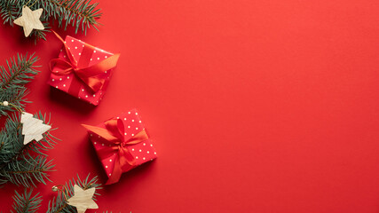 Christmas gifts and fir branches on red background with copy space. Christmas banner mockup, greeting card template. Flat lay, top view.