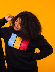 Young beautiful african american girl with an afro hairstyle. Portrait on yellow background.