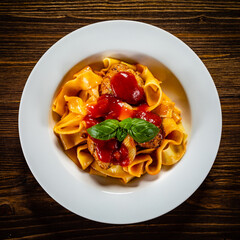 Pasta with meatballs in tomato sauce on wooden table
