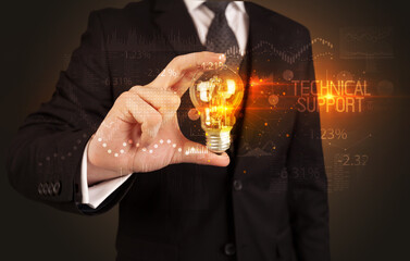 Businessman holding lightbulb with TECHNICAL SUPPORT inscription, Business technology concept