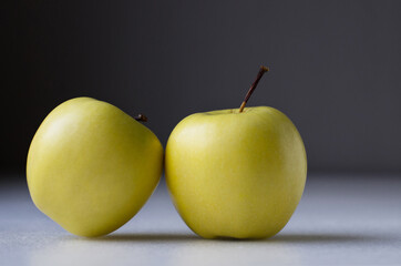 Apples, two yellow apples on a grey background.