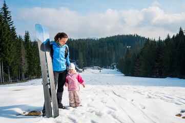 Mother and daughter posing at ski resort prepared to ride slopes.