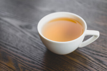 hot tea in white ceramic cup on vintage wooden table