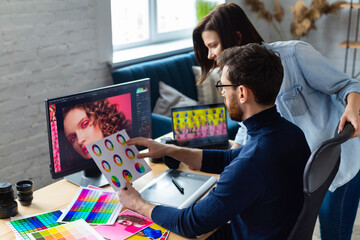 Photographer and graphic designer working in office with laptop, monitor, graphic drawing tablet and color palette. Creating team discussing ideas in advertising agency. Retouching images. Teamwork.