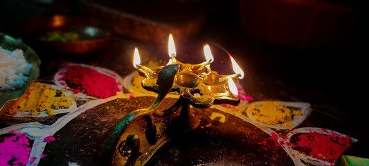 A glowing Multi Flame Lamp commonly known as Panchapradip. A holy thing used as an offering to God for worship. Surrounded by colourful Rangoli.