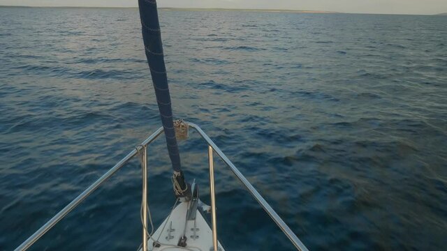 Up view of curtailed sail and jib furler on yacht sailing on river Volga. Water surface and sky are on backgorund.