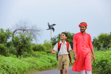 Indian farmer and his child playing with pinwheel on road side after school