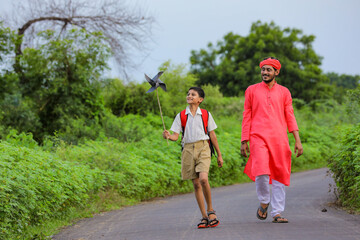 Indian farmer and his child playing with pinwheel on road side after school