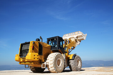 A big loader holding huge marble block. Loader machinery working on marble quarry with cloudy sky